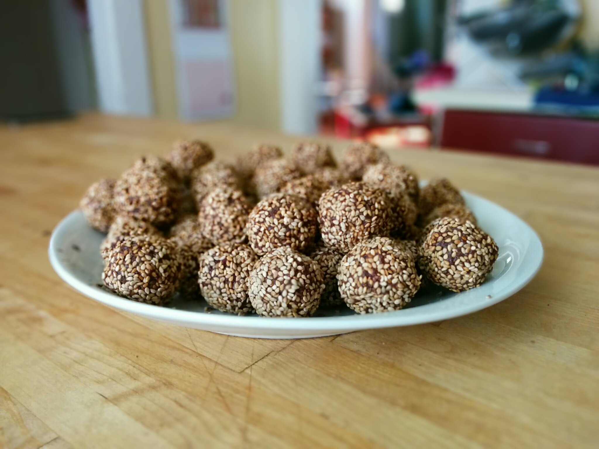 Photo of a plate of bliss balls, rolled in sesame seeds